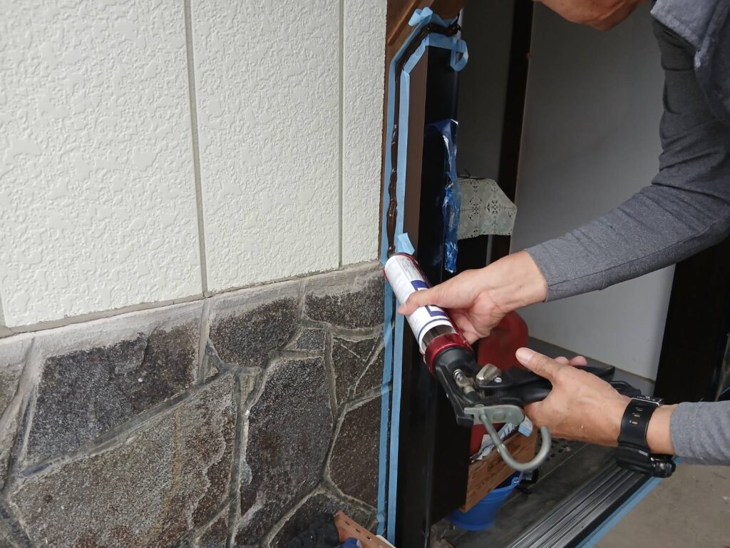 枠と外壁取り合いにコーキングガンでシールを打っている様子