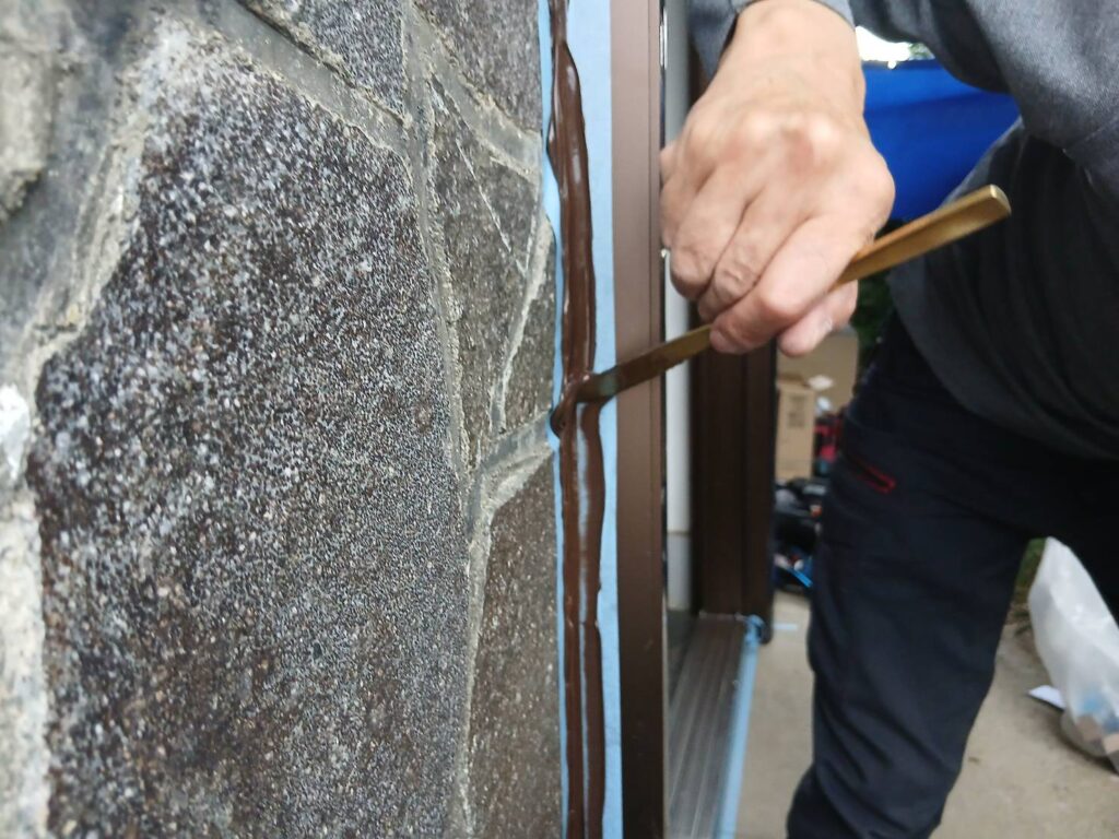 コーキング材をヘラで押さえて均している作業風景