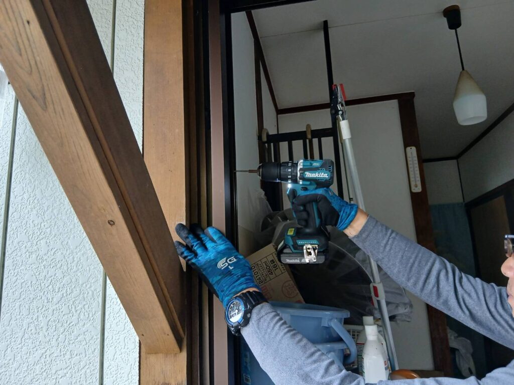 鴨居側の枠を電動ドリルで固定している職人