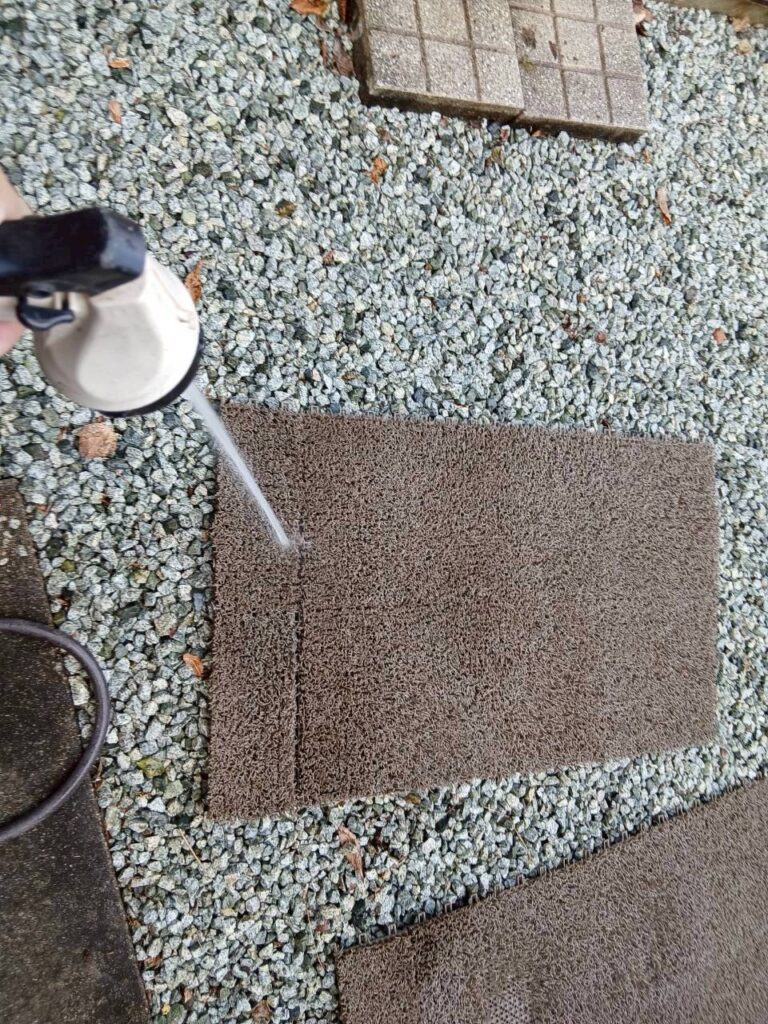 宮城県柴田郡のバルコニーでマットを水洗いして清掃している様子