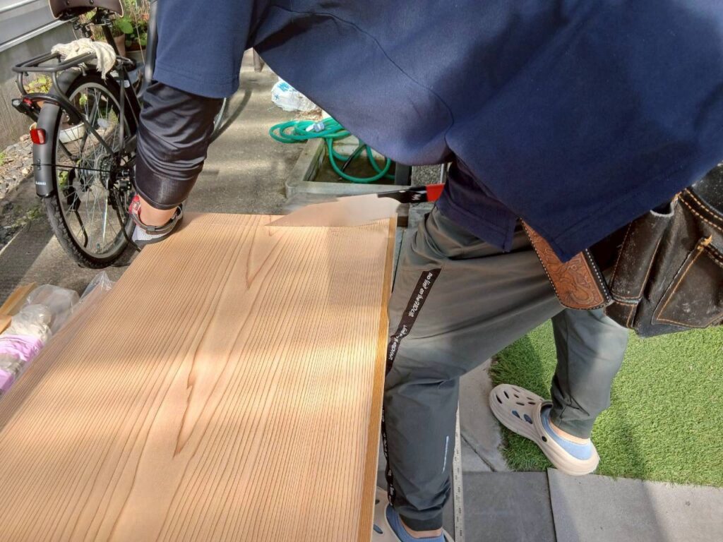 割れを防ぐため目透かし天井材を手鋸でカットして丁寧に加工している様子