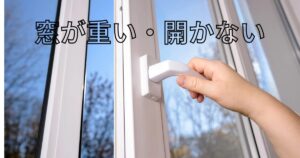 窓が重くて開かず、ハンドルを握って力を入れている様子（戸車やサッシ不具合のサイン）