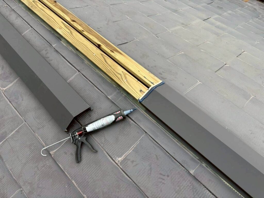 棟板金の取り付け中。重なり部分にコーキングを施し防水性を高めている様子