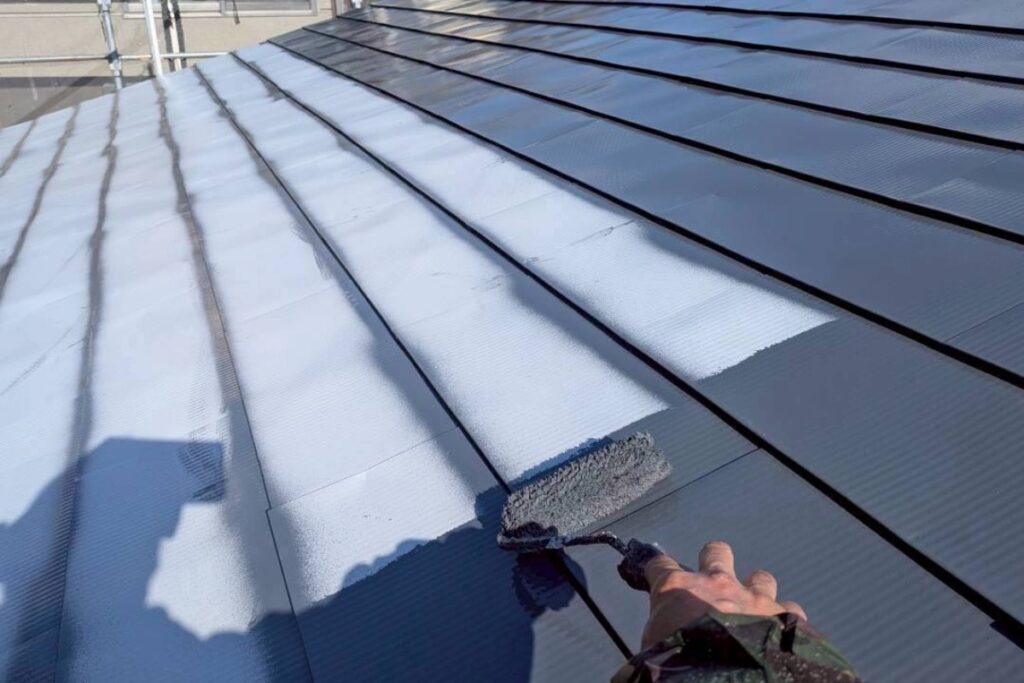 屋根の中塗り塗装をローラーで施工している塗装作業中の様子