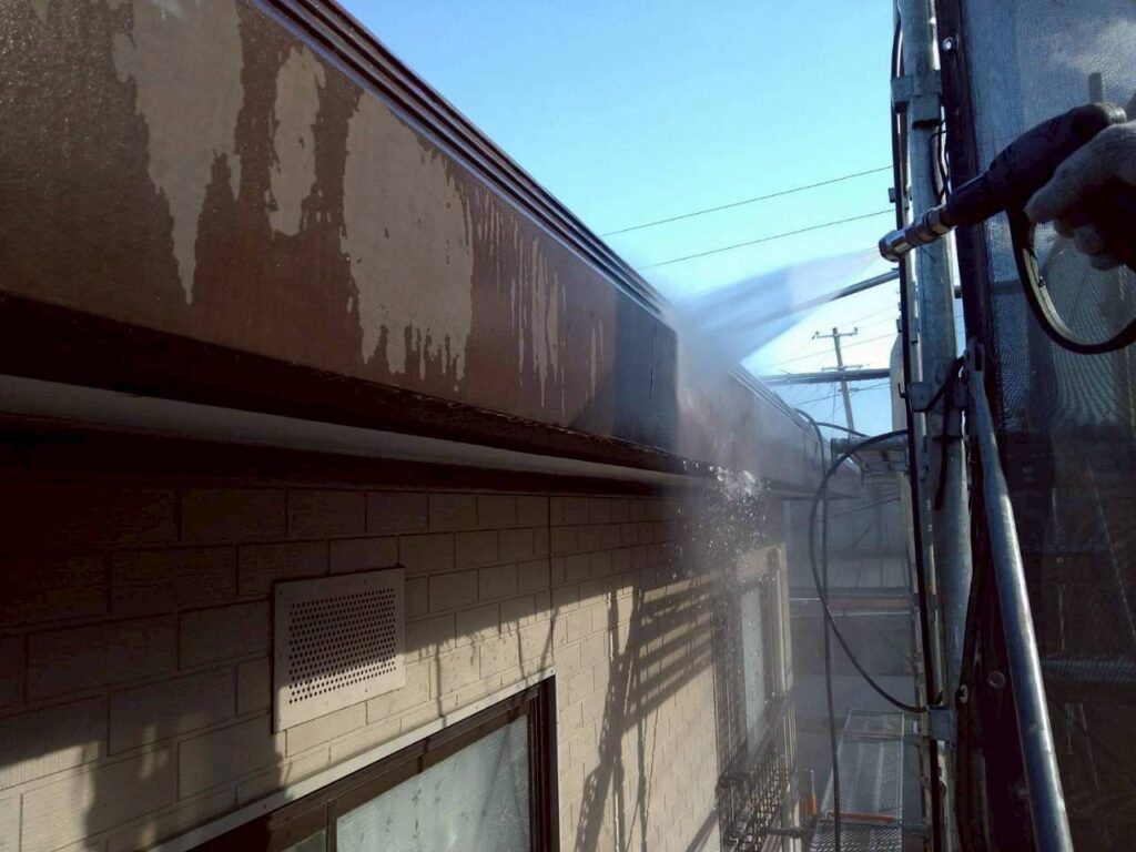 破風（パラペット）を高圧洗浄して汚れを落としている作業写真