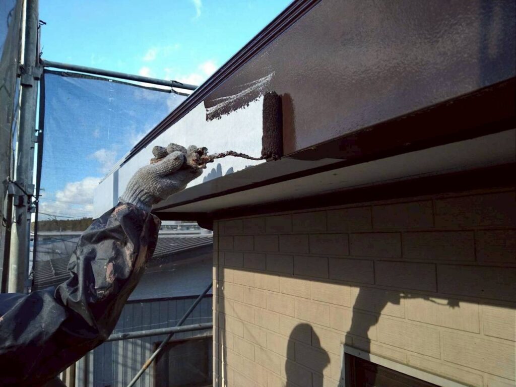 破風（パラペット）の中塗り塗装を行っている作業写真