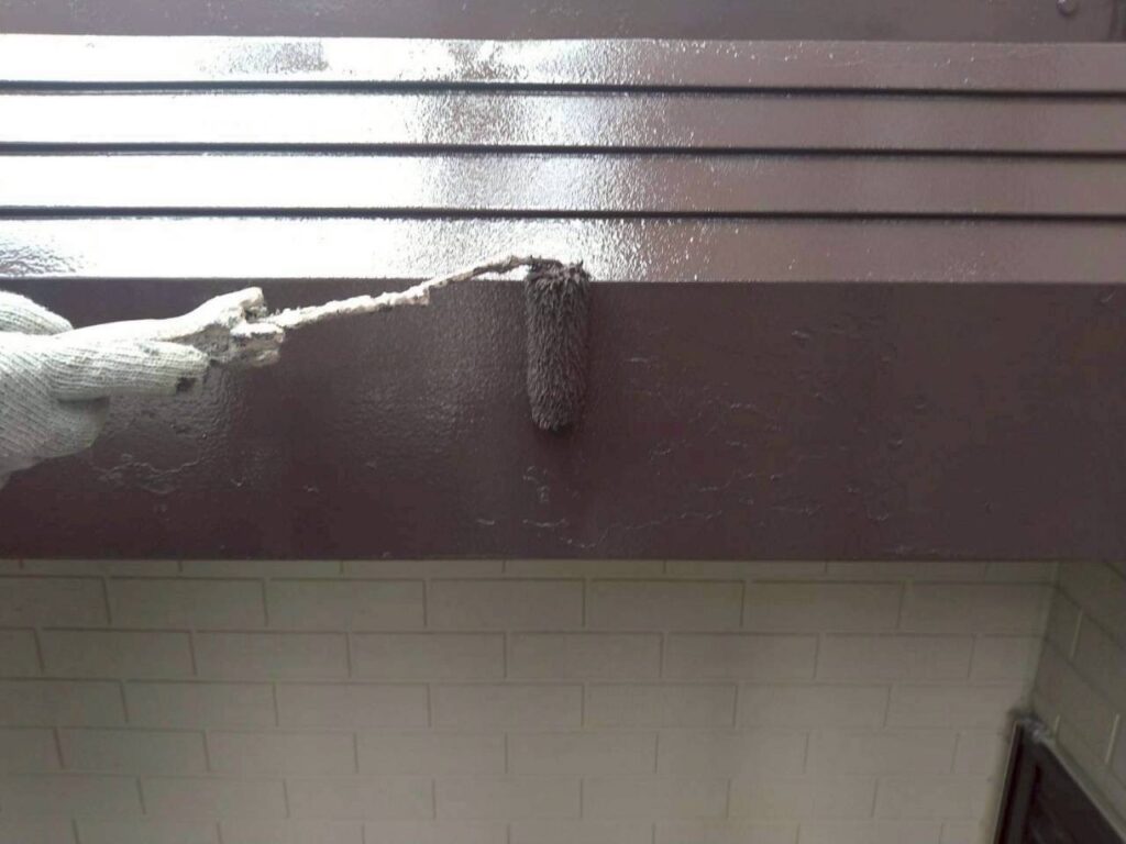 破風（パラペット）の上塗り塗装を行っている仕上げ作業