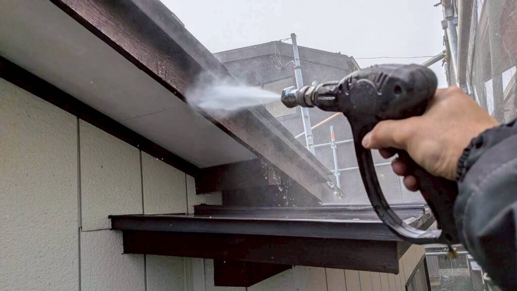 破風板塗装前に行う高圧洗浄作業の様子。旧塗膜や汚れを洗い流し、下地を整えている。