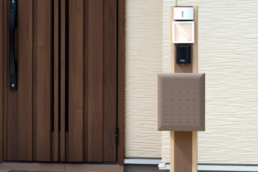 玄関前の門柱に設置された門柱タイプのポストとインターホンが一体になった外構設備。