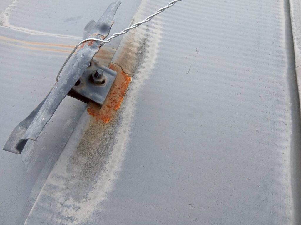 テレビアンテナに引っ張られて外れかけている雪止め金具の劣化状況