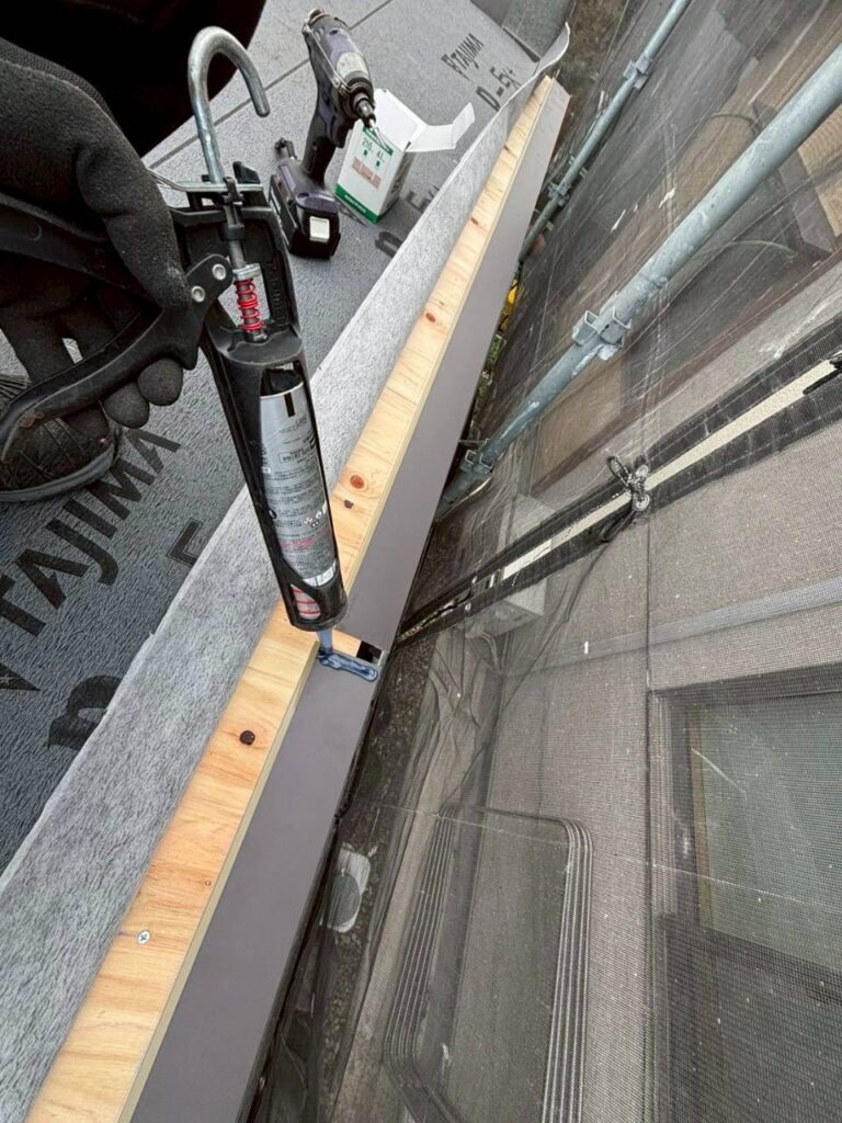 ケラバ板金の重なり部分にコーキング処理をして防水している様子