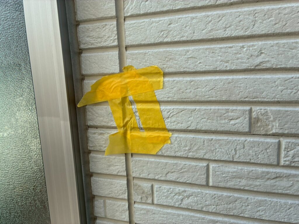 外壁ひび割れ補修のためマスキングテープで丁寧に養生している作業中の様子