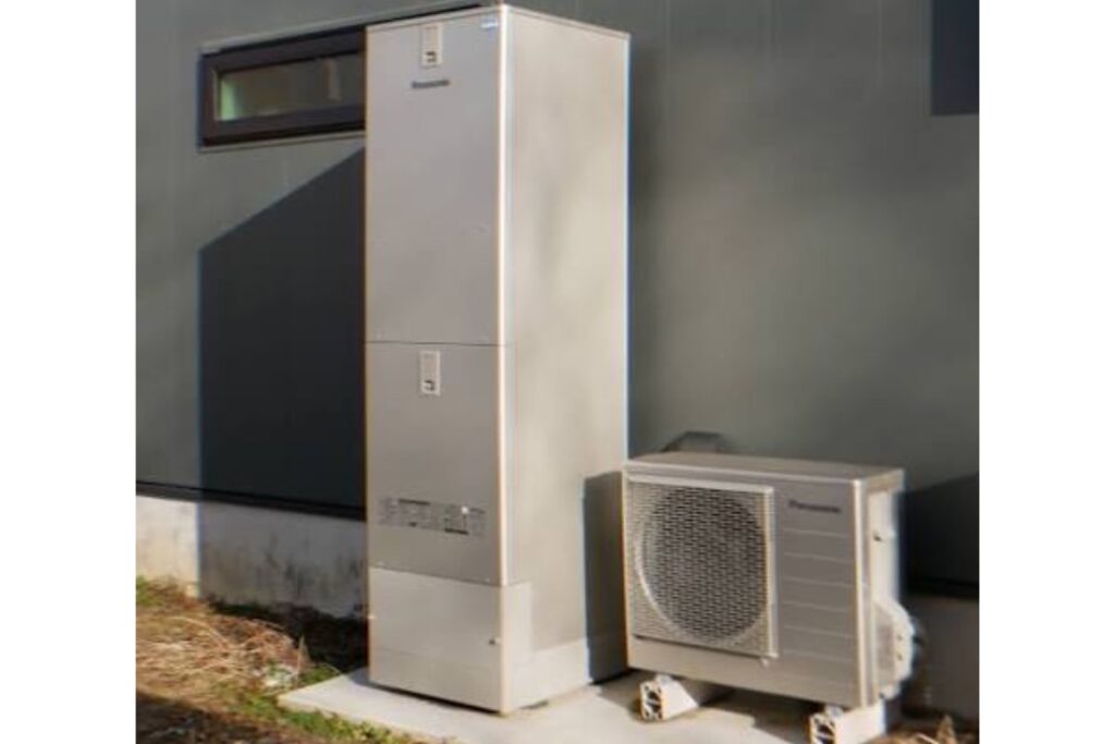 住宅外壁のそばに設置されたエコキュートとヒートポンプユニットの写真。交換時期や費用相場を解説する記事用画像。