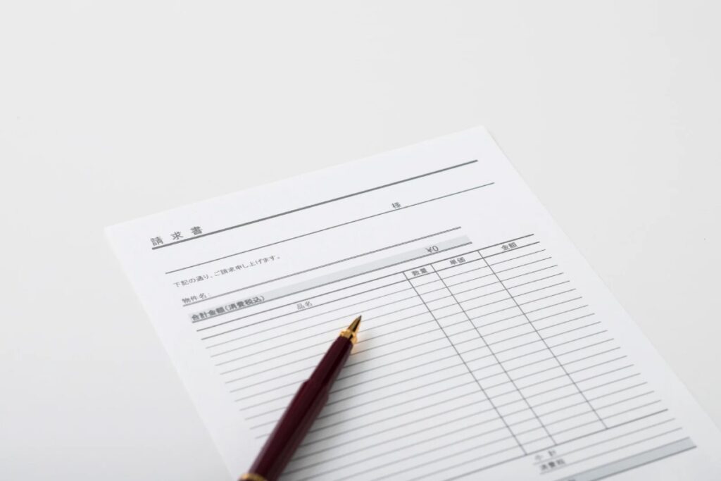 外壁塗装の見積書とペン。金額や内訳が分かりにくい業者選びに悩むイメージ