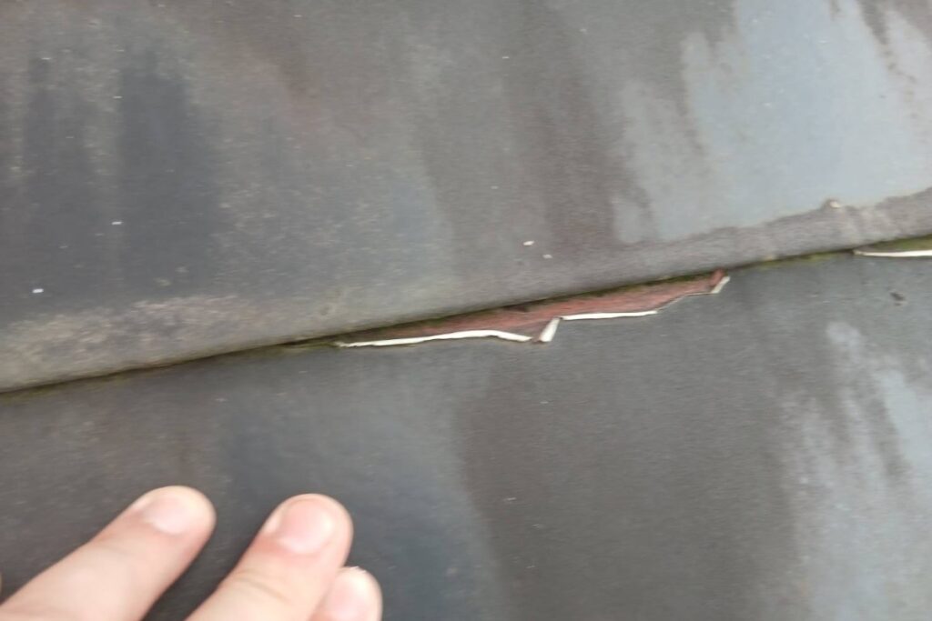 外壁塗装前の屋根材に発生したひび割れと劣化状況を現地調査で確認している様子