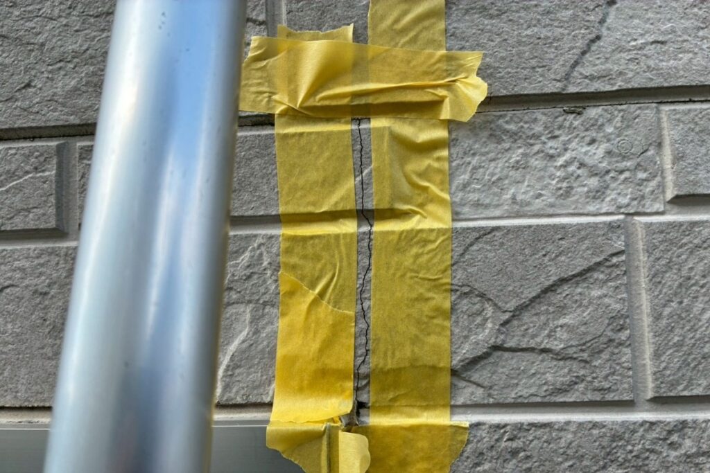 外壁のヒビ割れ周辺をマスキングテープで養生している様子