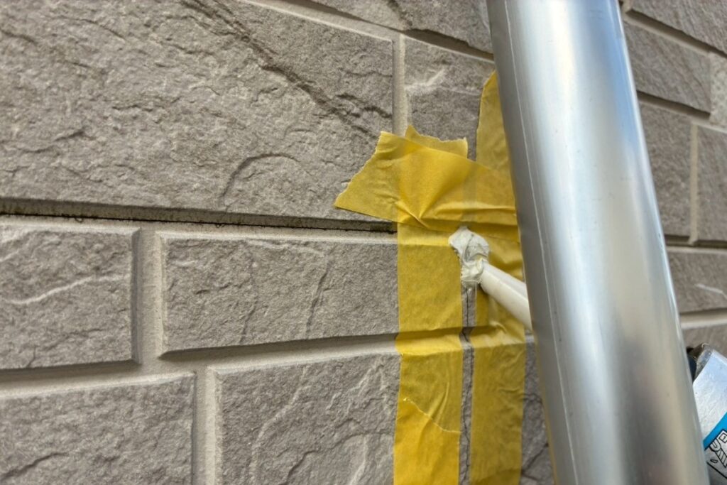 外壁のヒビ割れ部分にコーキング材を充填している作業中の写真