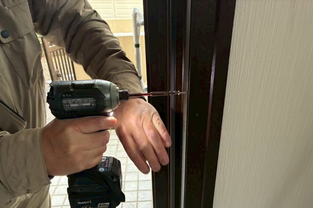 玄関ドア枠のビス固定作業（仙台市カバー工法）