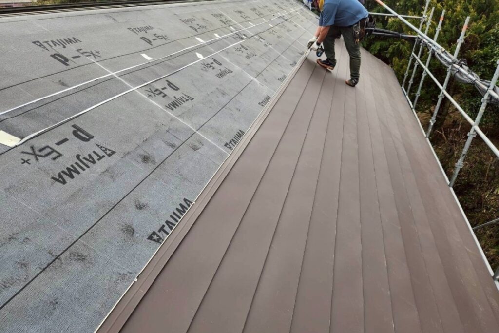 新しい屋根材を施工している屋根カバー工事の様子