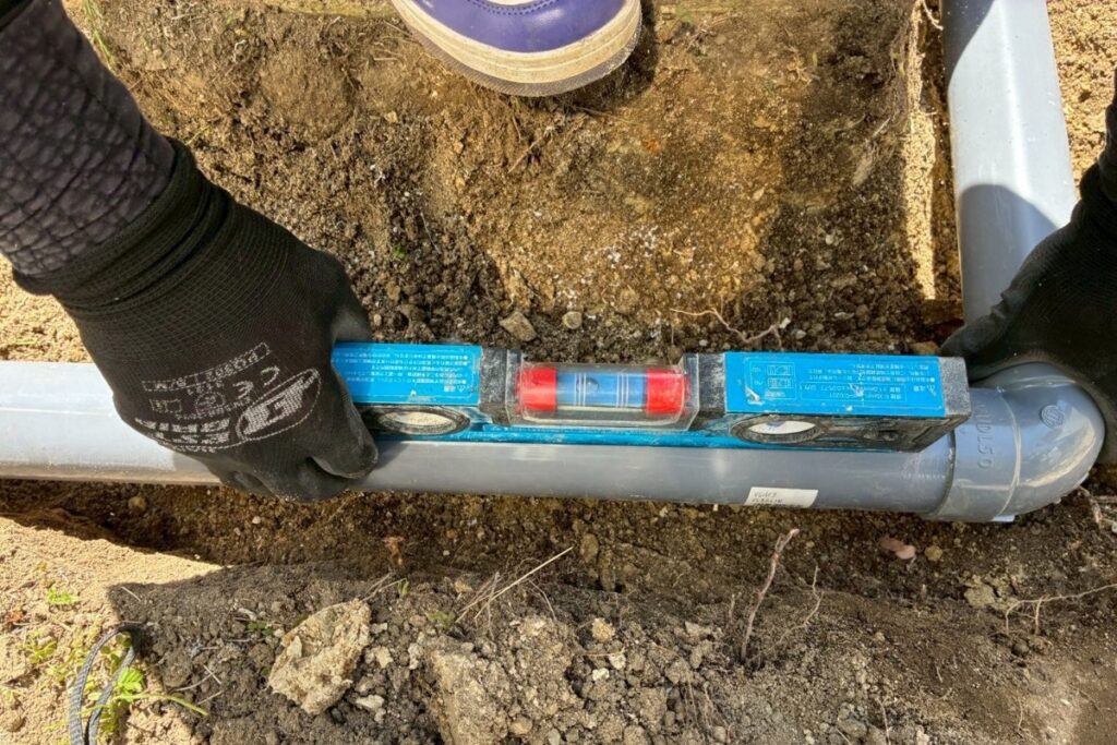 雨樋排水管の勾配を水平器で確認している施工中の様子