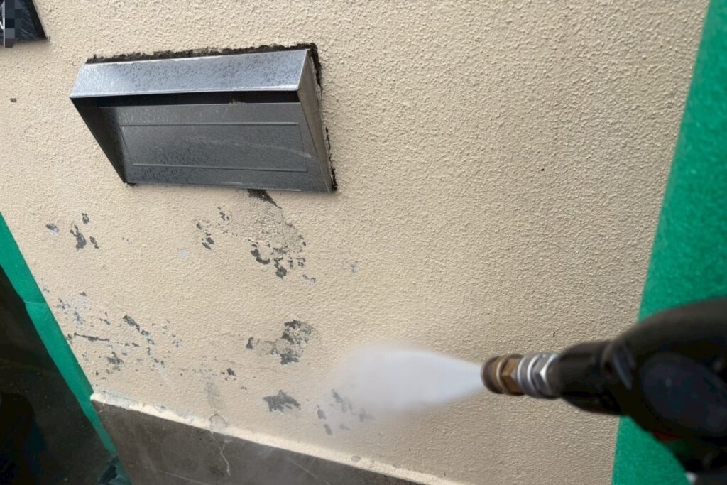 擁壁の汚れや旧塗膜を高圧洗浄で洗い流す作業